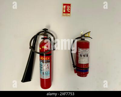 Two fire extinguishers mounted on a wall in Delhi, India, with a fire extinguisher sign above them. Stock Photo