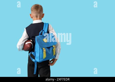 Little schoolboy with blue backpack and rugby ball on orange background ...