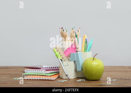 Pencil holder, notebooks, different school supplies and green apple on table against grey background Stock Photo