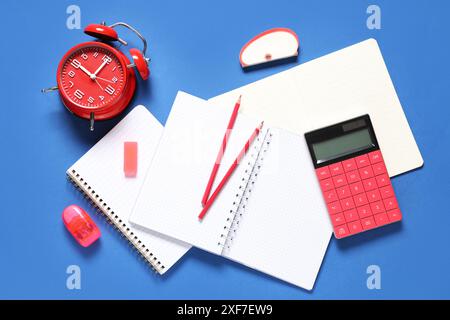 Alarm clock and different stationery on blue background Stock Photo