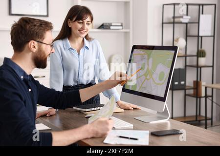 Cartographers working with cadastral map on computer at table in office Stock Photo