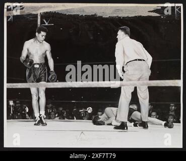 Boxer Joe Louis (1914-1981) (left) looks at Billy Conn (1917-1993)  (lying on canvas) after Conn was knocked out at the World Heavyweight Championship, New York, New York, June 18, 1941. Referee Eddie Joseph stands nearby. Photo by William C Greene/New York World-Telegram and the Sun Newspaper Photograph Collection Stock Photo