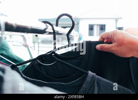 Human hands hanging washed clothes on a clothesline in the house , Housework concept Stock Photo