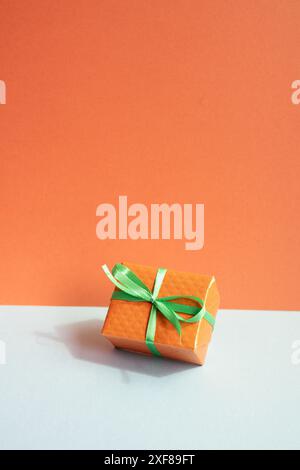 Orange gift box on gray desk. red wall background Stock Photo