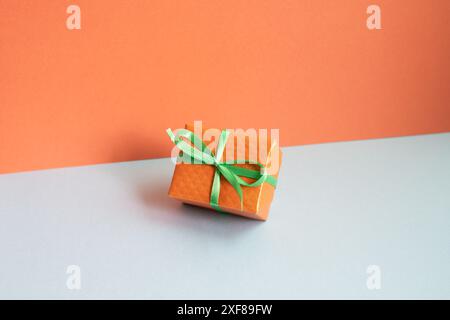 Orange gift box on gray desk. red wall background Stock Photo