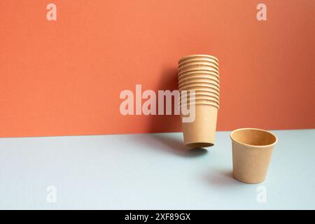 Disposable kraft paper cups on gray table. red wall background Stock Photo