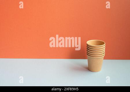 Disposable kraft paper cups on gray table. red wall background Stock Photo