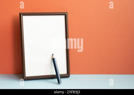 Empty photo frame with colored pencil on gray shelf. red wall background Stock Photo