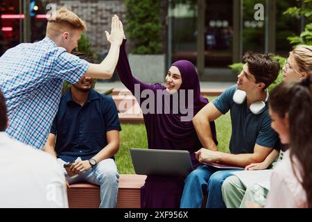 Outdoor meeting for common studying. Group of diverse students studying together for finals in the school courtyard. Stock Photo