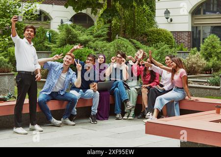 International classmates having fun, taking selfie for common memories in the outdoor campus seating area. Stock Photo