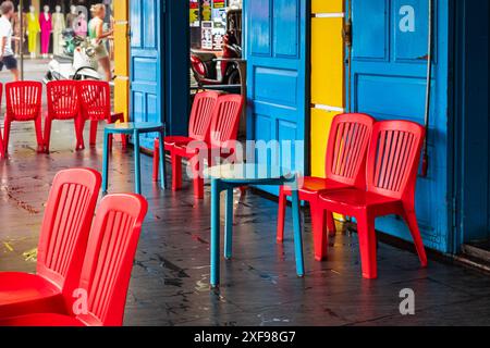 Colorful chairs and small tables in a street side cafe are inviting people to sit down. Cafe summer terrace, cozy tables with red chairs. Restaurant z Stock Photo