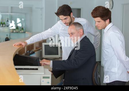apprentices and teacher behind the counter of a hotel reception Stock Photo