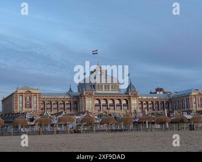 Large historic building with Dutch flag on the beach under a blue sky, scheveningen, the netherlands Stock Photo