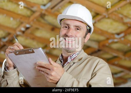 middle aged handyman wearing hardhat and holding clipboard Stock Photo