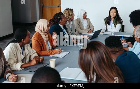 A multiethnic team engaged in a collaborative meeting workshop, focusing on discussion and teamwork. Diverse professionals working together around a c Stock Photo