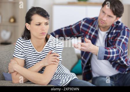 man supporting upset girlfriend while sitting together on couch Stock Photo