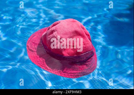 Bright pink sun hat, floating in a vivid blue, swimming pool Stock Photo
