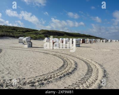 Row of beach chairs on sandy beach in front of dunes under blue sky with clouds, Spiekeroog, north sea, germany Stock Photo