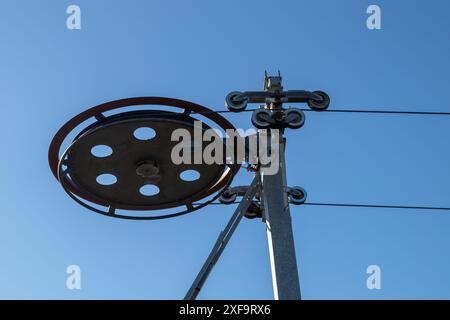 Ski lift wires and wheel against a blue sky background Stock Photo