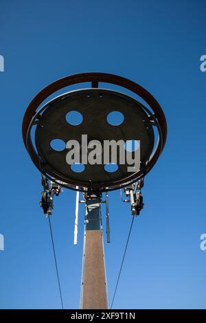 Ski lift wires and wheel against a blue sky background Stock Photo