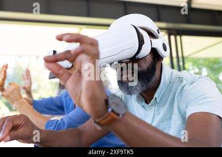 Using VR headset, senior man exploring virtual reality with friends Stock Photo