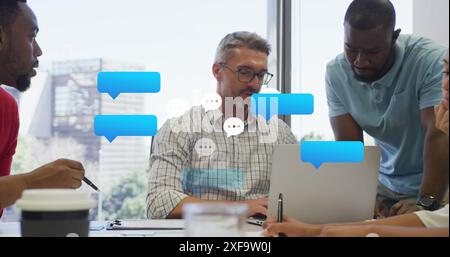 Image of black speech bubbles floating against diverse men discussing together at office Stock Photo