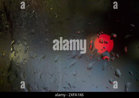 Raindrops on Window with Night Time City Lights Bokeh in Background Stock Photo