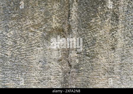 Old stone wall texture with a huge crack from through the middle of the photograph. Traces of machining still visible. Stone is weathered. Stock Photo