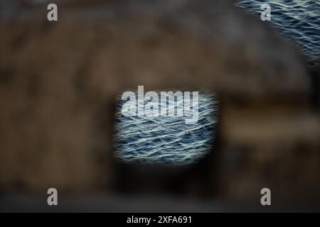 Sea water texture shot through a window hole in an old brick wall. Stock Photo