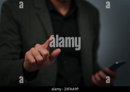 businessman is holding smartphone and pointing index finger against background Stock Photo