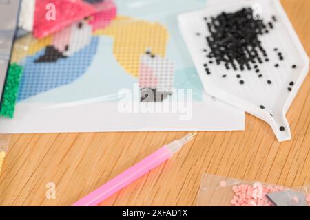 A close-up of a hand placing crystals on a canvas for a diamond painting project. Diamond Mosaic Stock Photo