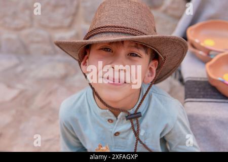 portrait of latino boy face looking at the camera smiling with a cowboy hat. Concept of happy childhood Stock Photo