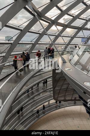 Berlin, Germany - Dec 20, 2023 - Several tourists walking at ramps inside the futuristic glass dome. A curved walkway stretches in spirals upwards on Stock Photo