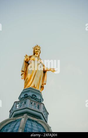 Lyon, France. June 10, 2024. Golden statue of the Virgin Mary sculpted by Joseph-Hugues Fabisch in 1852 on top of a steeple in the Basilica Fourvière Stock Photo