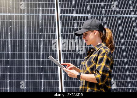 A female engineer performs maintenance on a solar power plant, collecting operational panel data using a digital tablet Stock Photo
