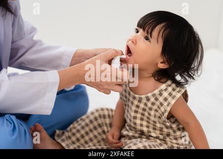 doctor spraying medicine in teeth of toddler girl. baby decayed tooth protect concept Stock Photo