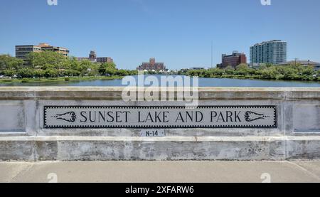 sunset lake and park sign on pond with view of asbury park paramount theater and convention center building in background new jersey shore travel beac Stock Photo