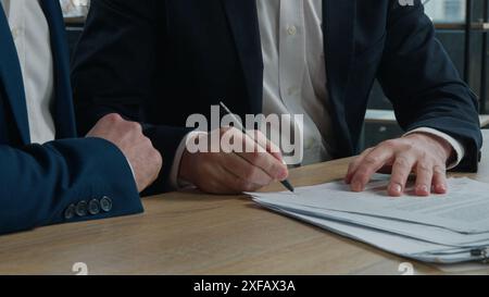Close-up two unrecognizable businessmen men business partners signing contract document conclude successful financial deal at meeting in office sign Stock Photo