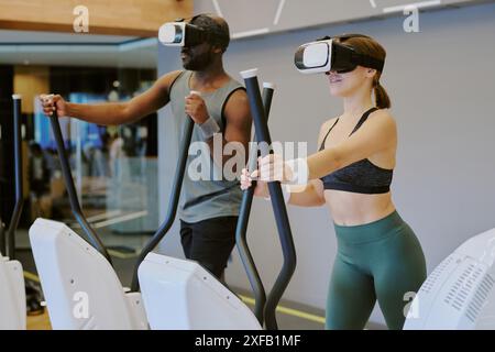 Young biracial couple having fun with VR headset and playing game while they doing cardio for summer season Stock Photo