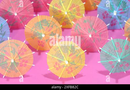 Multicolored Cocktail Umbrellas, spring and summer symbol, pink background, shallow depth of field Stock Photo