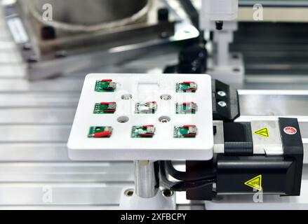 Factory machinery at work, A small printed circuit board is assembled into an automated robotic arm Stock Photo