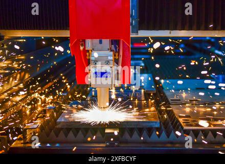 Industrial laser cut machine while cutting the sheet metal with the sparking light. Stock Photo