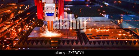Industrial laser cut machine while cutting the sheet metal with the sparking light. Stock Photo