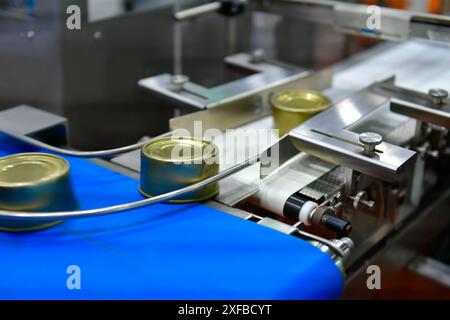 Canned food products on conveyor belt in distribution warehouse. parcels transportation system concept. Stock Photo