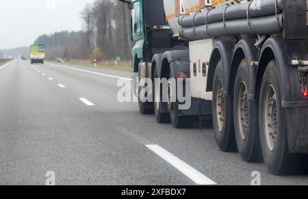 A tanker semi-trailer truck transports a dangerous cargo of gasoline, diesel fuel and petroleum products on the road against the backdrop of the sun. Stock Photo