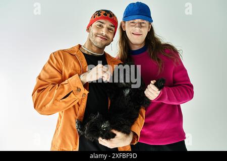two men joyfully hold a black dog together. Stock Photo
