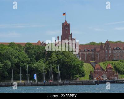 Historic castle with German flag on hill above the sea, boats in the water, green forest, flensburg, schleswig-holstein, germany Stock Photo