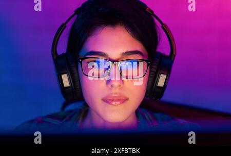 Young Woman Wearing Glasses and Headphones While Using PC Stock Photo