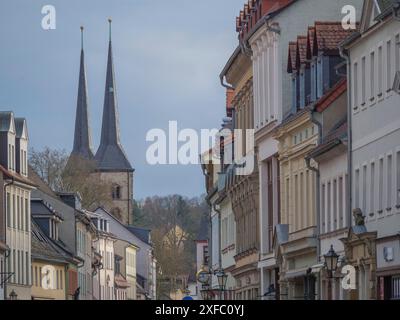 City street lined with historic buildings and towers rising into the sky under a partly cloudy sky, grimma, dresden, germany Stock Photo