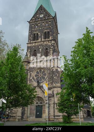 Large Gothic church with a high church tower and rose windows, surrounded by trees, under a stormy sky, Herten, North Rhine-Westphalia, Germany Stock Photo